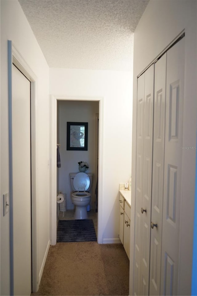 bathroom featuring vanity, a textured ceiling, and toilet