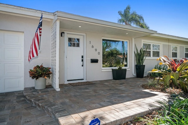 entrance to property featuring a garage and a patio area