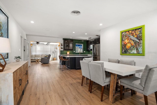 dining area with ceiling fan, sink, and light wood-type flooring