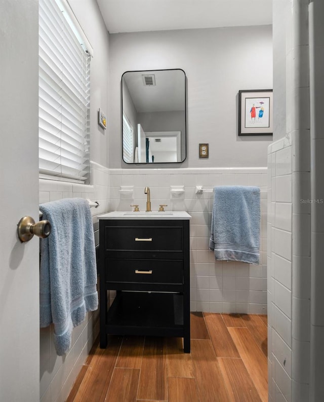 bathroom featuring vanity, hardwood / wood-style floors, and tile walls