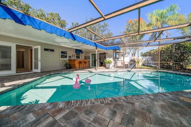 view of swimming pool with a patio, an outdoor bar, and glass enclosure