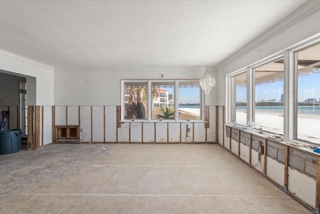 empty room with a water view, crown molding, and a chandelier