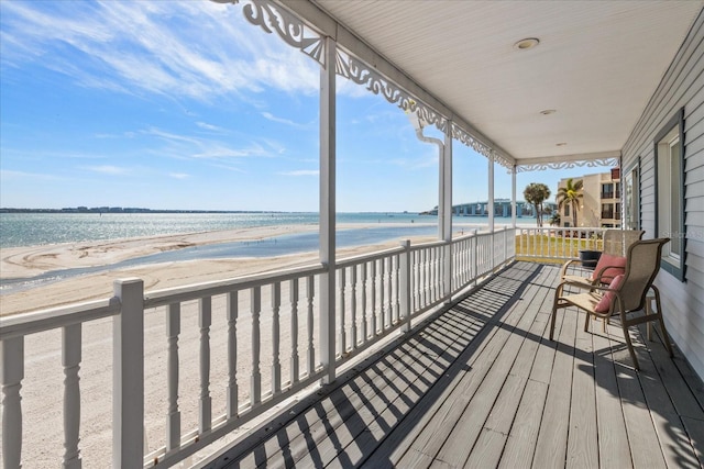 wooden deck featuring a water view and a beach view