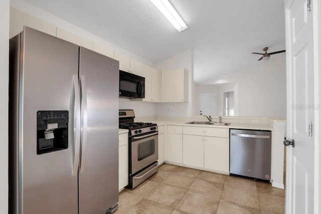 kitchen featuring sink, light tile patterned floors, vaulted ceiling, and appliances with stainless steel finishes