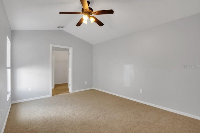 carpeted spare room featuring ceiling fan and vaulted ceiling