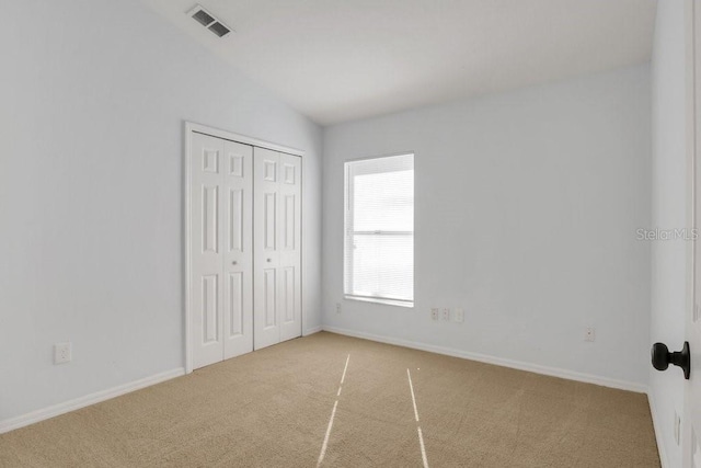 unfurnished bedroom with lofted ceiling, carpet floors, and a closet