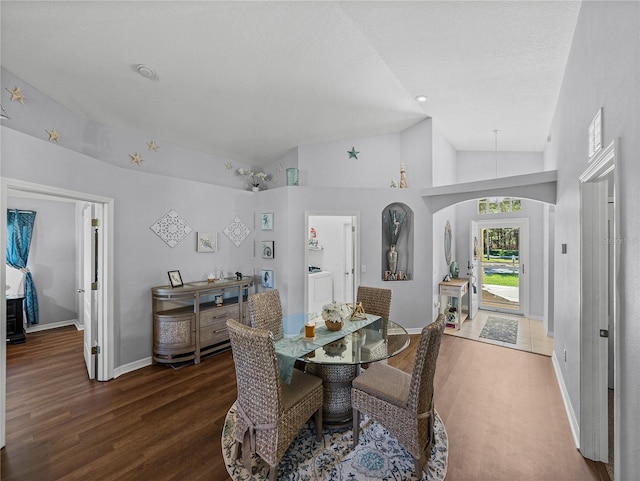 dining area featuring high vaulted ceiling, washer / clothes dryer, and dark hardwood / wood-style floors