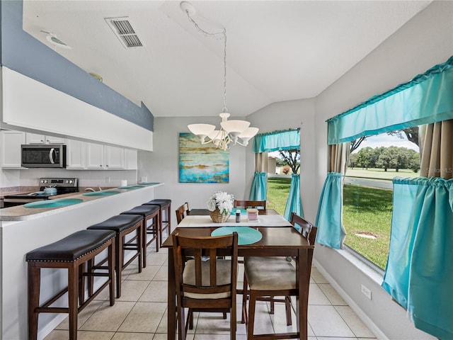 dining space with light tile patterned floors, a chandelier, and vaulted ceiling