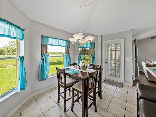 tiled dining space with vaulted ceiling and an inviting chandelier