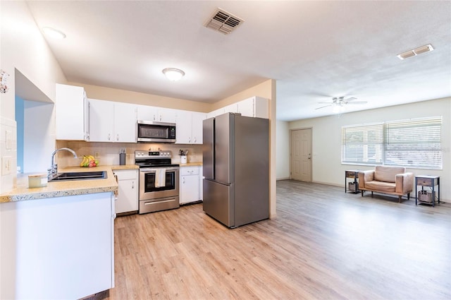 kitchen with sink, white cabinetry, tasteful backsplash, light wood-type flooring, and appliances with stainless steel finishes