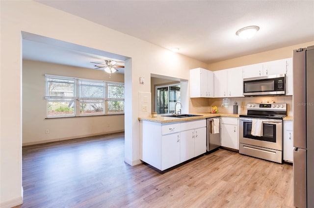 kitchen featuring sink, white cabinetry, stainless steel appliances, light hardwood / wood-style floors, and decorative backsplash