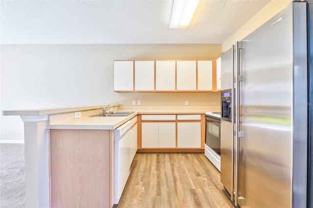 kitchen featuring sink, white appliances, light hardwood / wood-style flooring, a textured ceiling, and kitchen peninsula