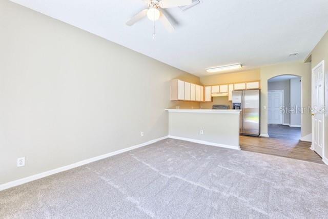 unfurnished living room featuring ceiling fan and carpet flooring