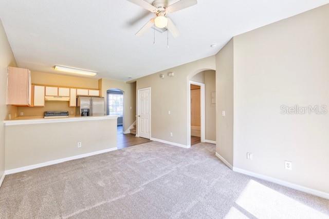 unfurnished living room with light carpet and ceiling fan