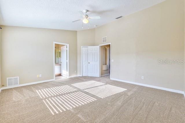 carpeted spare room with a textured ceiling, vaulted ceiling, and ceiling fan