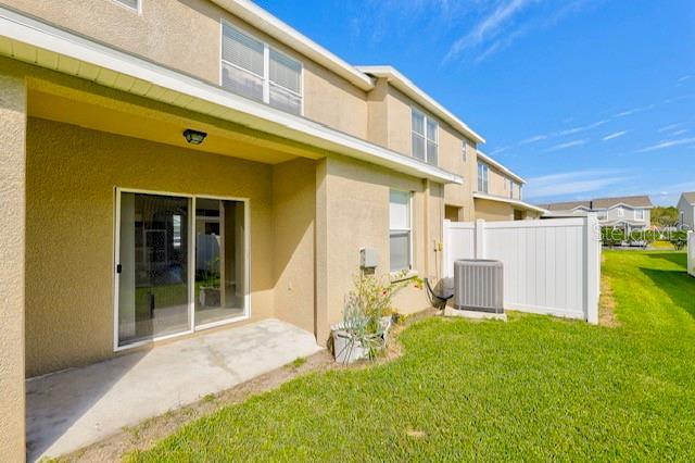 back of property featuring cooling unit, a lawn, and a patio area