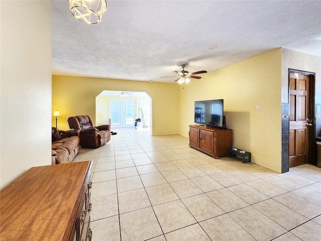 tiled living room with ceiling fan and a textured ceiling