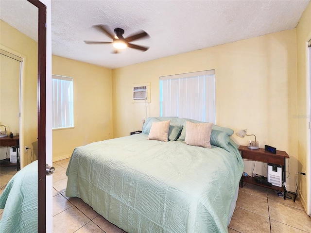 bedroom featuring light tile patterned flooring, a wall mounted AC, ceiling fan, and a textured ceiling