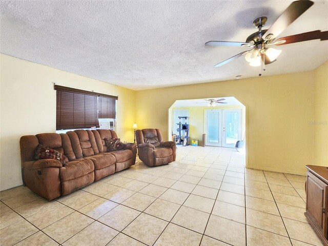 living room featuring ceiling fan, a textured ceiling, and light tile patterned floors