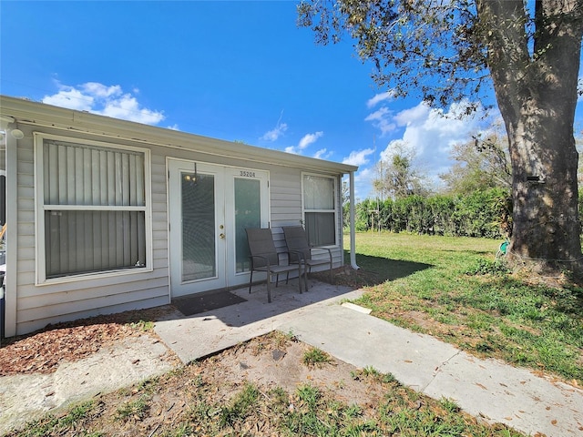 entrance to property with a patio area and a lawn