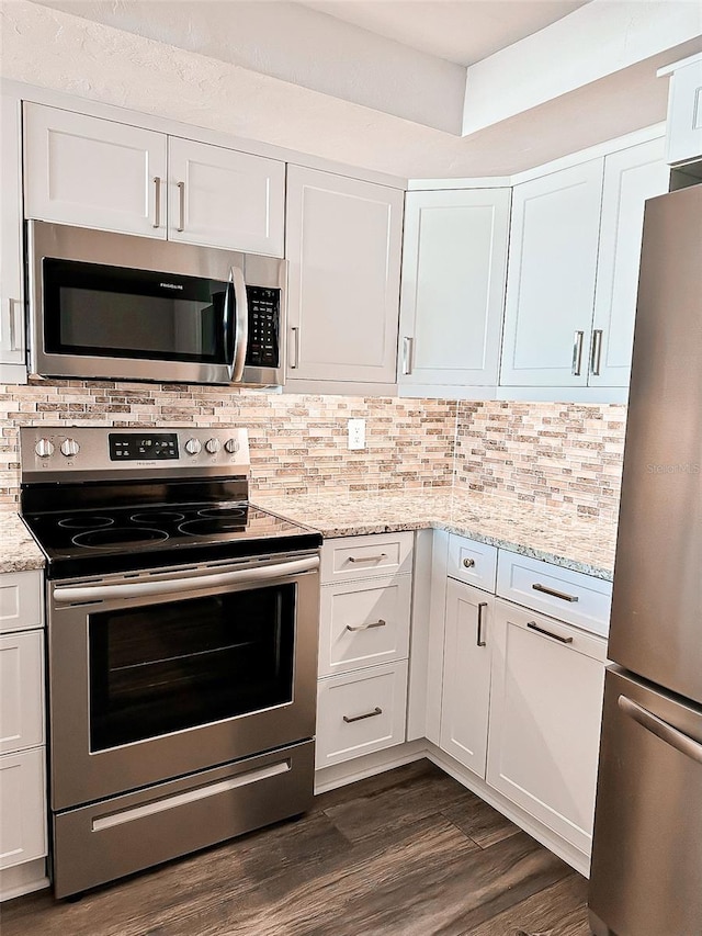 kitchen with appliances with stainless steel finishes, decorative backsplash, white cabinetry, and dark hardwood / wood-style floors