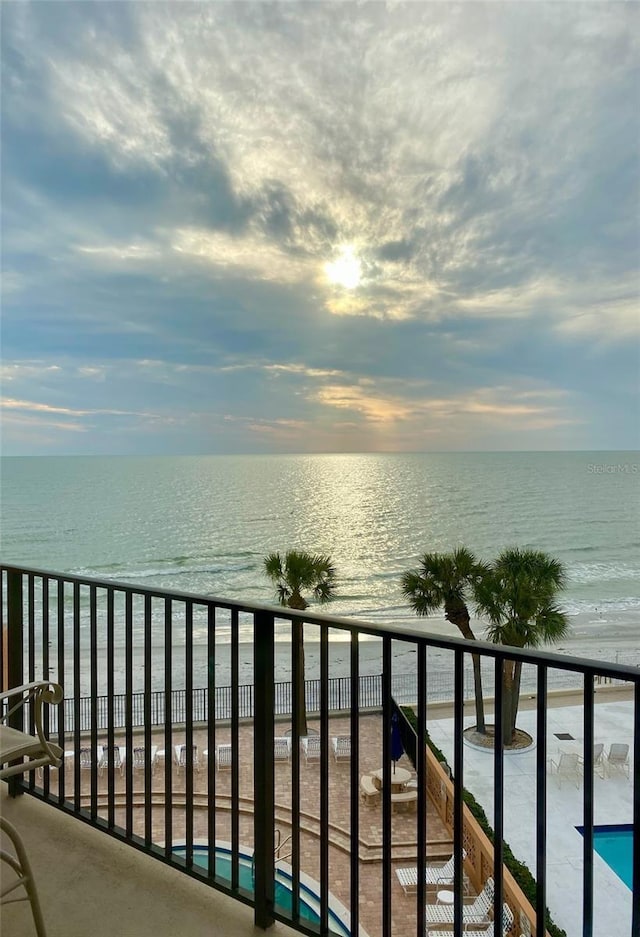 balcony with a water view and a view of the beach