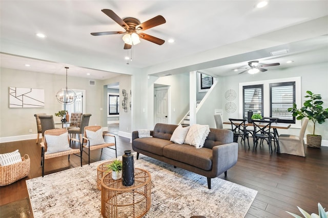 living room with dark wood-type flooring and ceiling fan with notable chandelier