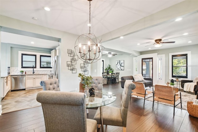 dining space featuring sink, ceiling fan with notable chandelier, and light wood-type flooring