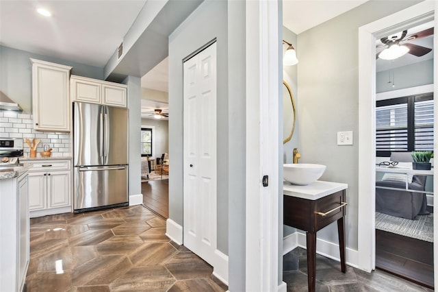 interior space featuring sink, stainless steel fridge, ceiling fan, stove, and tasteful backsplash