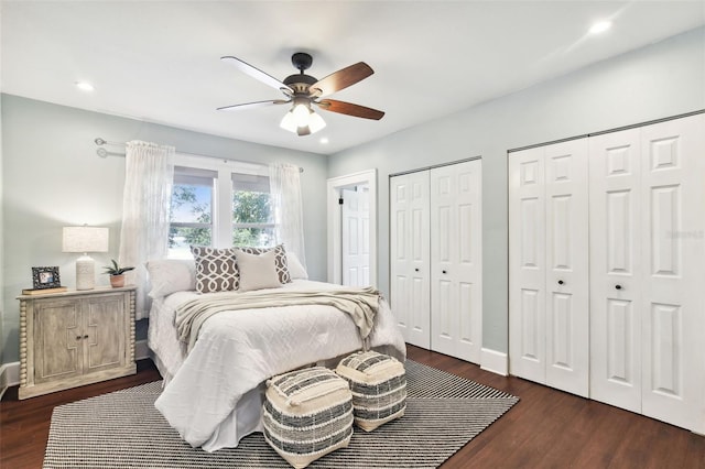 bedroom featuring dark hardwood / wood-style flooring, two closets, and ceiling fan