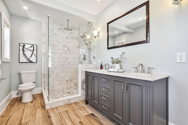 bathroom featuring vanity, wood-type flooring, toilet, and tiled shower