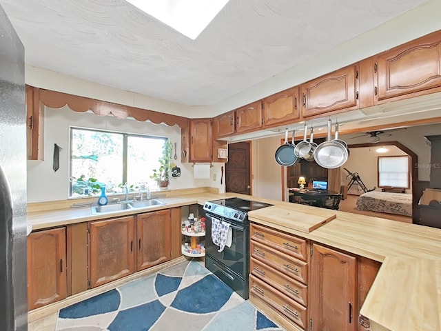 kitchen featuring butcher block counters, black electric range oven, and sink