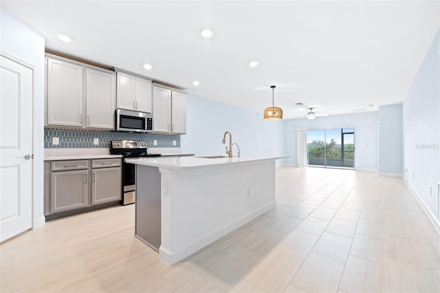 kitchen with gray cabinets, sink, decorative backsplash, hanging light fixtures, and stainless steel appliances