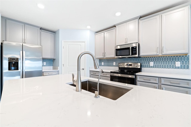 kitchen featuring light stone countertops, appliances with stainless steel finishes, sink, and decorative backsplash