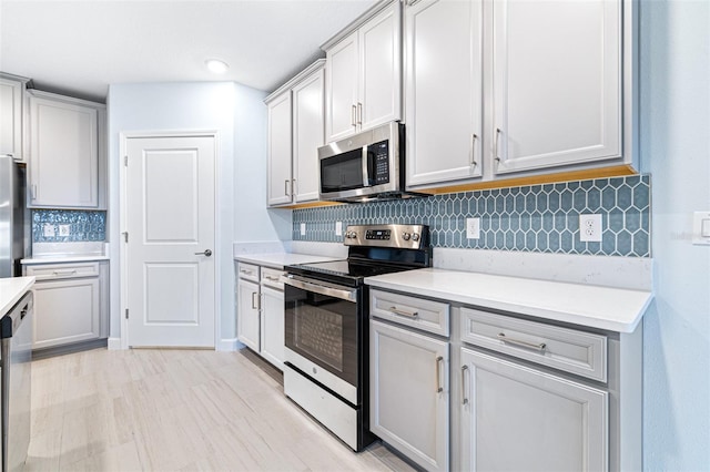 kitchen featuring stainless steel appliances, light wood-type flooring, and backsplash