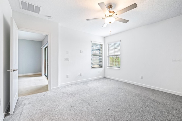 carpeted empty room with ceiling fan and a textured ceiling