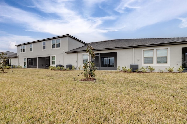 rear view of house featuring a lawn, a sunroom, and central air condition unit