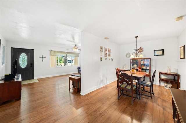 dining area featuring wood-type flooring and ceiling fan with notable chandelier