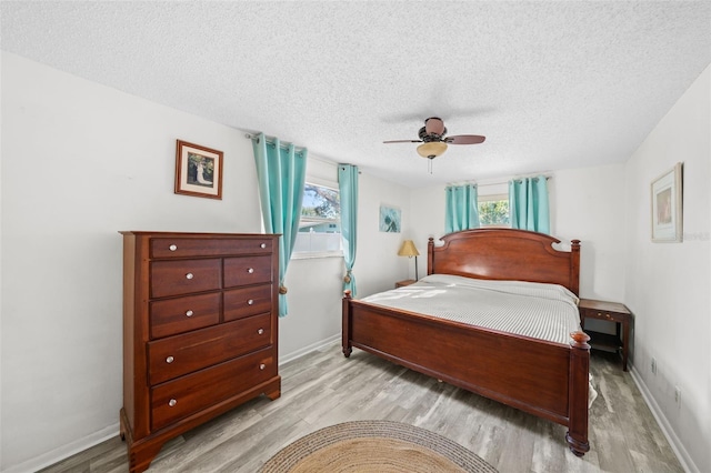 bedroom with ceiling fan, light hardwood / wood-style flooring, and a textured ceiling