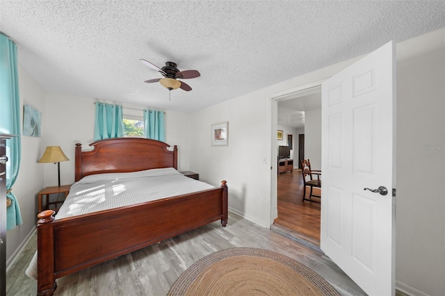 bedroom with a textured ceiling, light hardwood / wood-style floors, and ceiling fan