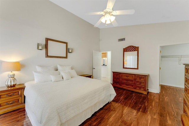 bedroom with dark wood-type flooring, lofted ceiling, a walk in closet, a closet, and ceiling fan