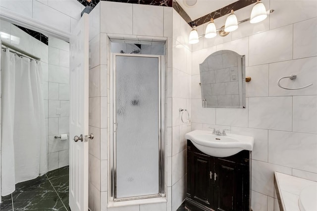 bathroom featuring vanity, a shower with shower door, and tile walls