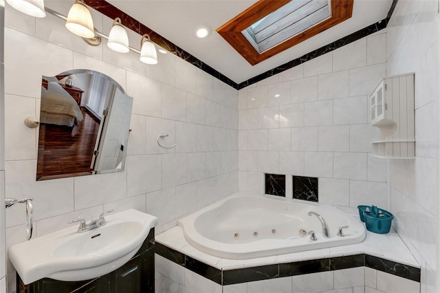 bathroom with lofted ceiling with skylight, tile walls, vanity, and tiled bath