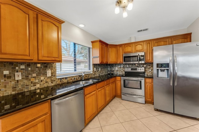 kitchen with light tile patterned flooring, appliances with stainless steel finishes, sink, and dark stone countertops