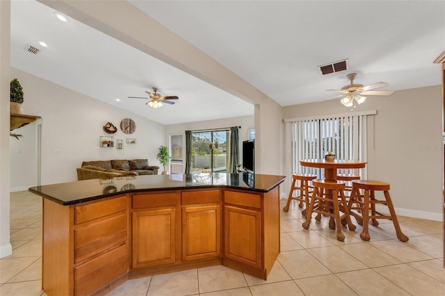 kitchen featuring lofted ceiling, a center island, light tile patterned floors, and ceiling fan