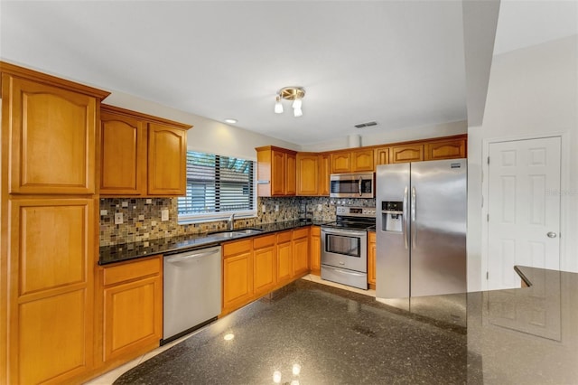 kitchen with tasteful backsplash, stainless steel appliances, sink, and dark stone countertops