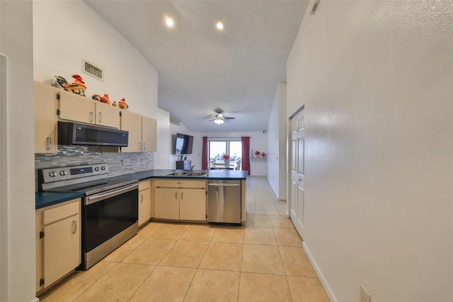 kitchen featuring cream cabinetry, sink, kitchen peninsula, and appliances with stainless steel finishes