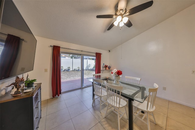 dining room featuring light tile patterned flooring, lofted ceiling, ceiling fan, and a textured ceiling