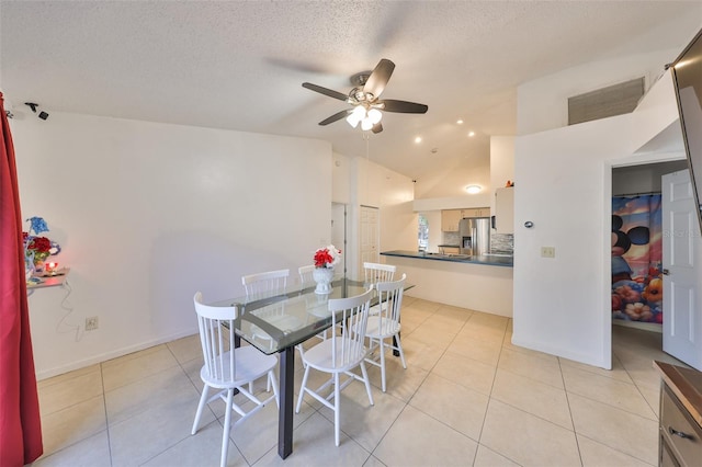 tiled dining room featuring vaulted ceiling, a textured ceiling, and ceiling fan