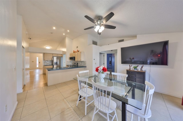 tiled dining space with ceiling fan, vaulted ceiling, and a textured ceiling